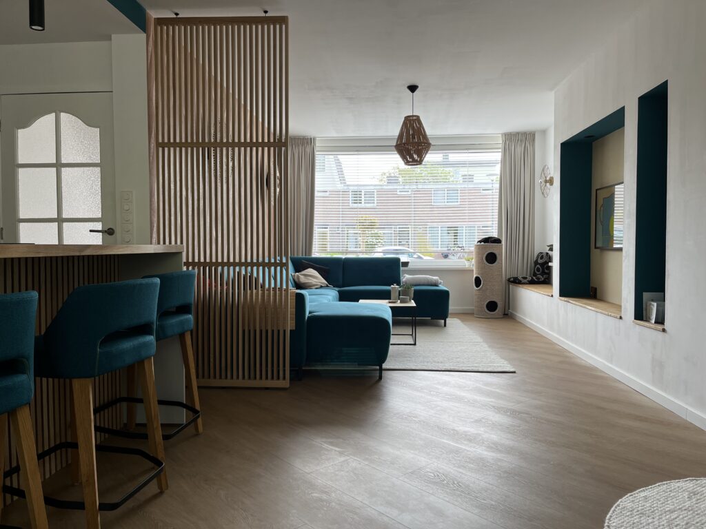 Laura's HI Design woonkamer kookeiland roomdivider hout wandmeubel kastenwand vloerkleed bank barkruk interieurontwerp kleuradvies lichtplan